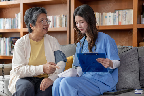 Bild auf Leinwand Female nurse holds clipboard checking senior woman patient at home during health