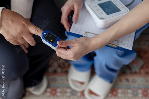 Photos Nurse checking patient oxygen saturation using pulse oximeter attached to finger