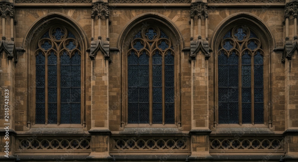 Fototapeta premium Three large Gothic windows on a brown stone building exterior wall