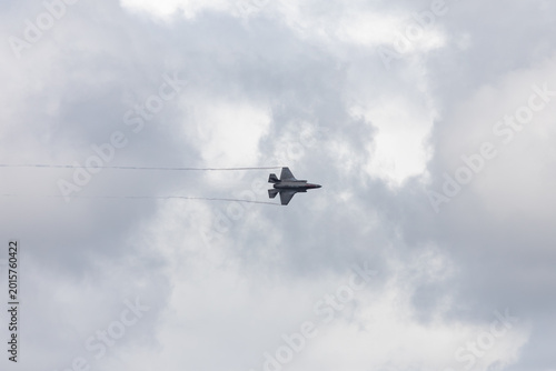 American 5th generation stealth fighter jet of the US Air Force performing aerial maneuvers in cloudy skies. Powerful modern military aircraft flying during aviation demonstration