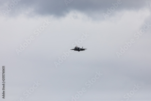 American 5th generation stealth fighter jet of the US Air Force performing aerial maneuvers in cloudy skies. Powerful modern military aircraft flying during aviation demonstration
