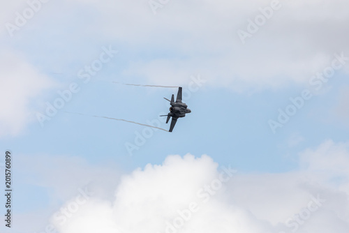 American 5th generation stealth fighter jet of the US Air Force performing aerial maneuvers in cloudy skies. Powerful modern military aircraft flying during aviation demonstration