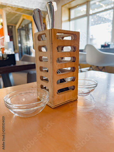 A Contemporary Dining Table Setting Featuring a Stylish Wooden Utensil Holder and Glass Bowls that Enhance the Aesthetic Appeal of the Restaurant Experience