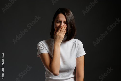 Foto Sad young woman crying and covering her mouth with her hand while feeling deep emotional pain