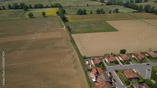 Aerial Fields and Homes: An expansive aerial perspective captures a harmonious blend of rural agriculture and residential community life. This scene. Caleppio, Lombardy, Italy