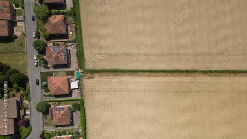 Aerial View of Residential Area and Farm Field: An eye-level aerial shot presents a captivating composition: on one side, a tranquil residential area of houses, and on the other, a vast field.