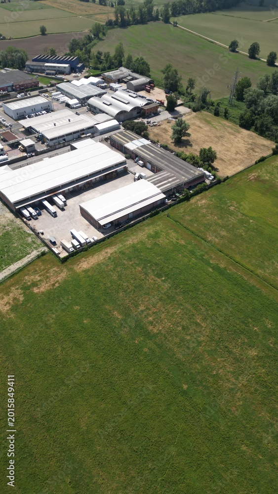 Obraz premium Industrial Landscape: An aerial perspective reveals an industrial complex nestled amidst verdant fields, a harmonious blend of manufacturing and natural surroundings.