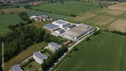 Industrial and office buildings captured from drone above Lombardy, Italy. Rooftop solar panels and clean architecture represent innovation, smart monitoring and sustainable industrial development.