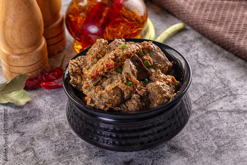 Canvas Print Hearty stewed chicken liver with herbs and spices in a black bowl on a gray table