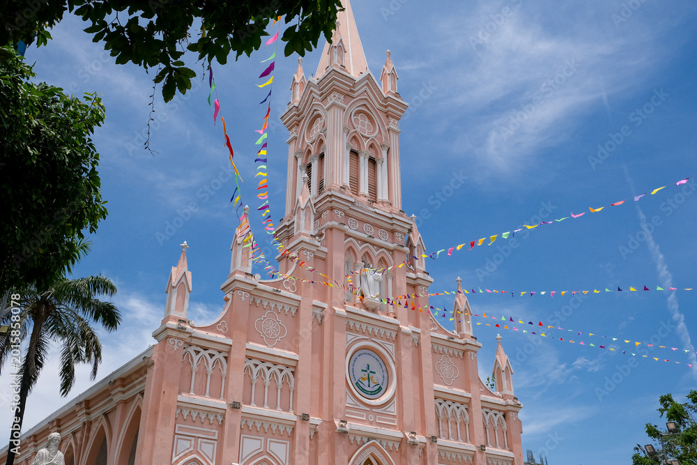 Fototapeta premium Pink Cathedral in Da Nang, Vietnam under blue sky with colorful festival flags