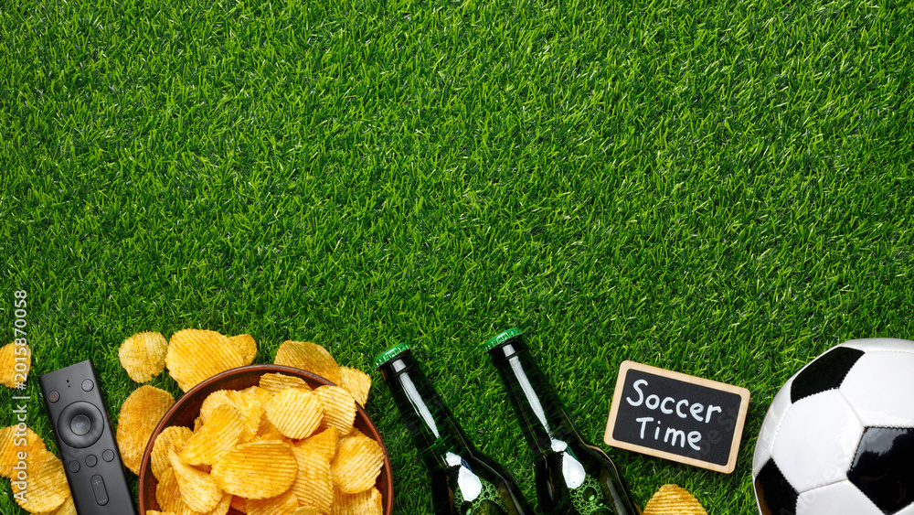 Naklejka premium Green beer bottles, potato chips, a classic soccer ball, TV remote and a small chalkboard sign 