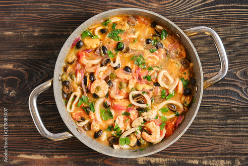 Foto Seafood dish in a pan with mixed ingredients and bright colors served on a woode