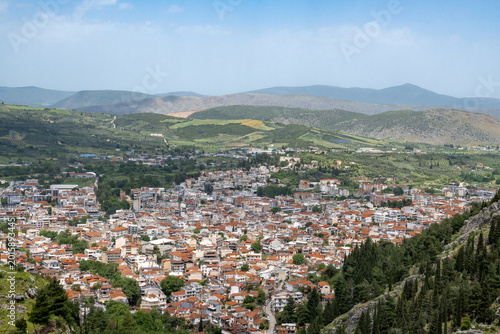 Panoramic photo of the Livadia city at Boeotia-Greece from the top of a mountain. Green fields and blue sky at the background.