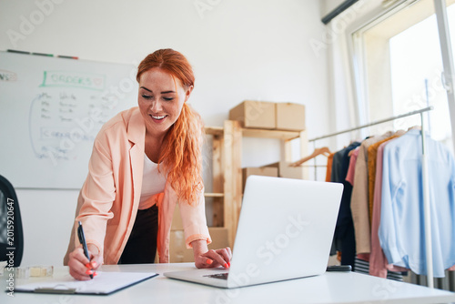 Fotografi Young woman managing online clothing store orders at desk