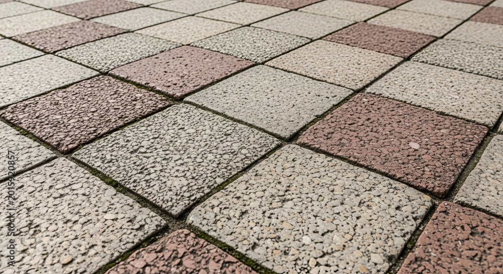 Fototapeta premium Close-up view of a rough, unpolished stone floor pattern with alternating tile colors and textures.