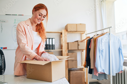 Young woman packing clothing order in small business office