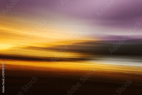 Abstract streaks of warm light blend with cool hues across a blurred landscape