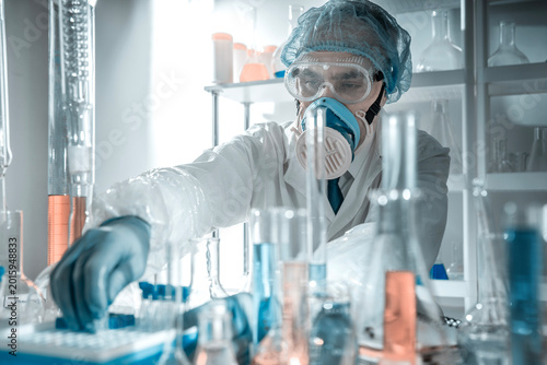 Scientist with chemical glassware in a laboratory. Concept of laboratory safety, hazardous substances, contamination control, scientific protocols and professional research environment.