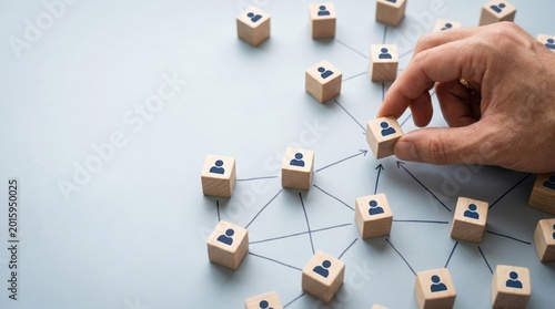 Human hand connecting block figures, symbolizing networking and team building. The hands carefully connect blocks with person icons. The image captures the essence of community