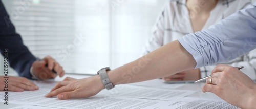 Photos Business people discussing contract documents on a white desk, analyzing clauses