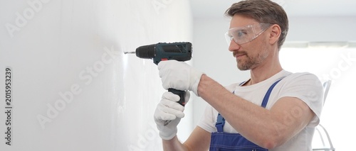 Fotografie Man professional construction worker in a blue jumpsuit, safety goggles, and wor