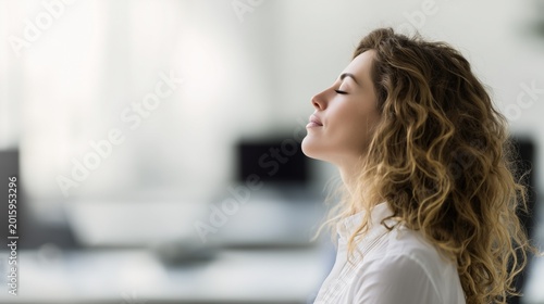 Office worker pausing to breathe quietly in a modern workspace, soft light