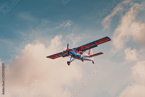 Small propeller plane flies through a partly cloudy, golden-hour sky