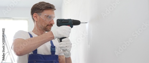 Photos Middle aged male construction worker in a blue jumpsuit, safety goggles, and wor