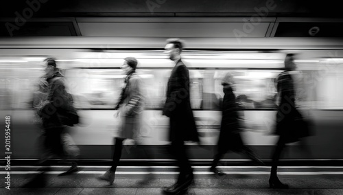Blurred motion of commuters on a platform as a train passes by