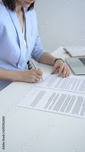 Businesswoman's hands writing on a document, formalizing a deal, agreement, or legal paperwork, illustrating concepts of expertise, negotiation, and corporate decision making