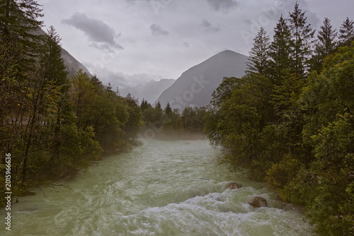 Tableau sur toile Soca river green waters rush in the rain as they cross the Julian Alps, seen eastward upstream from the Za Otoki footbridge