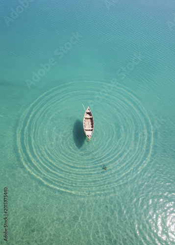 Aerial view of a small boat floating on turquoise water with ripples aerial view boat alone clear wa