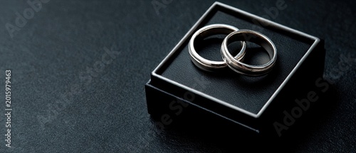A pair of white gold wedding rings, a black box. Empty space for text