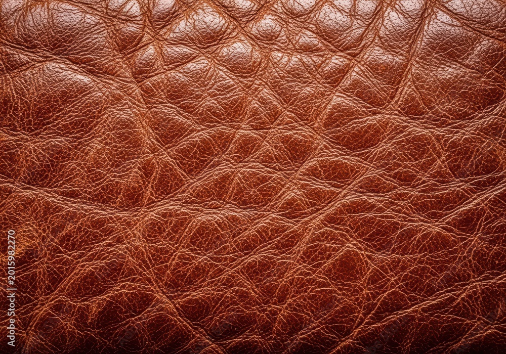 Fototapeta premium Close up of heavily textured brown leather surface showing wrinkles, scuffs, scratches, and deep patina from long use, ideal background, cracked, canvas, distressed