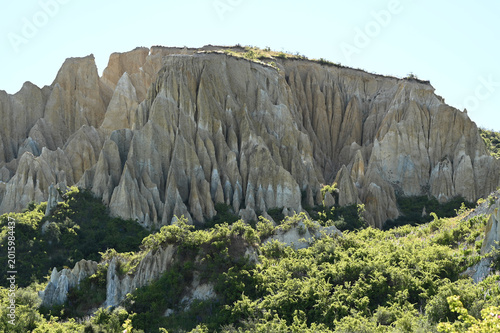Clay Cliffs and Sharp Pinnacles Under Bright Sunlight with Green Vegetation