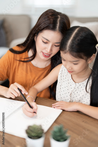 Asian Mother Guiding Daughter with Homework at Home