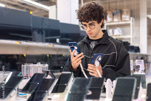 Tableau sur toile Teenage boy choosing smartphone in electronics store