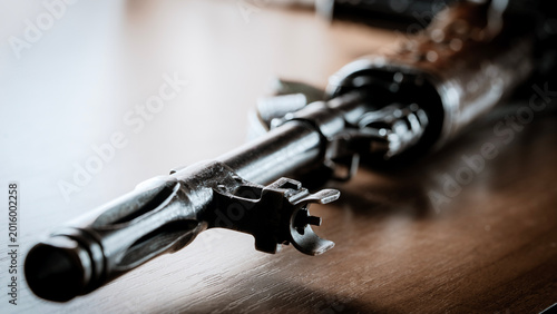 Fotografie Metal gun rests on wooden surface