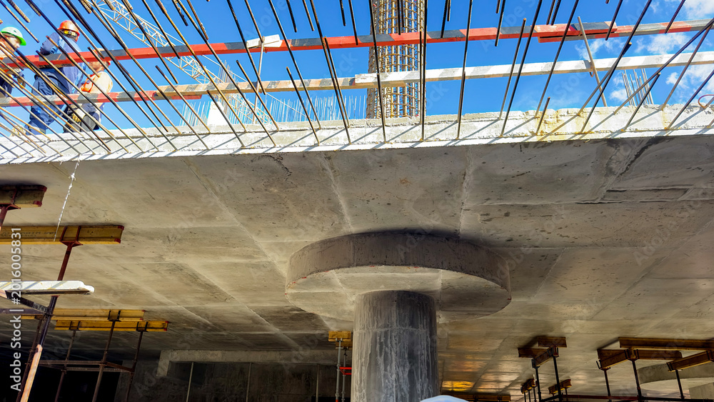 Fototapeta premium Construction workers build a massive concrete bridge