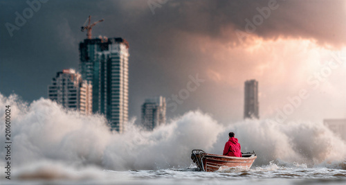 Man in red coat navigating small boat through giant ocean wave near city skyscraper. Global climate change and environmental disaster. Powerful storm surge flooding urban coastline.
