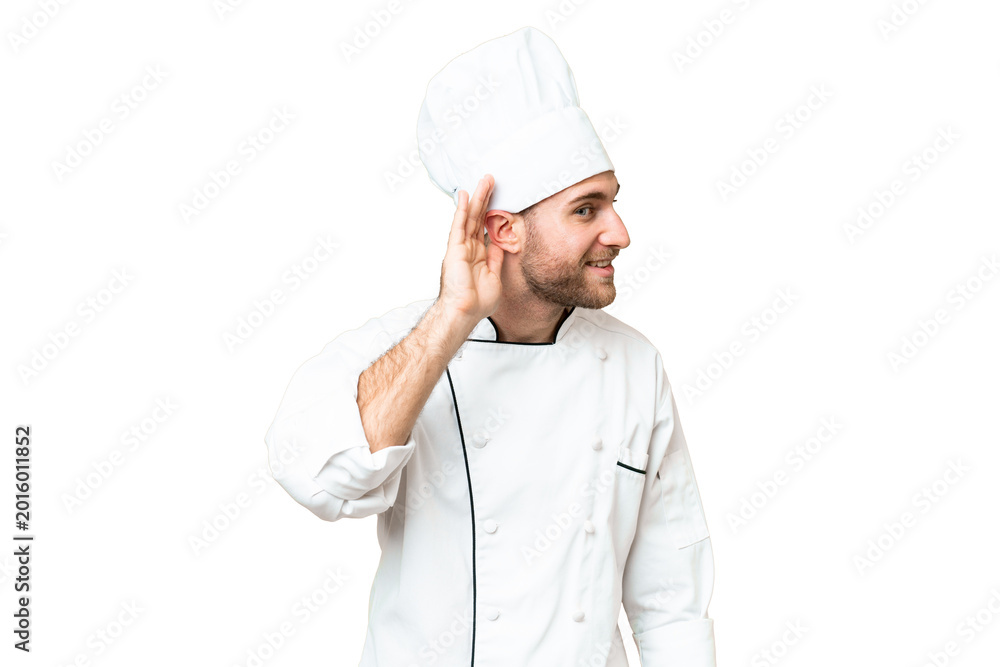 Fototapeta premium Young blonde man Chef over isolated chroma key background listening to something by putting hand on the ear