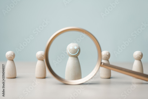 Magnifying glass highlighting happy figure among sad figures, representing mental health awareness, emotional support, therapy, resilience and positive wellbeing.