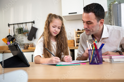 Father helping daughter with homework at home. Caring parent supporting child education, homeschooling, family bonding, and learning activities in a modern kitchen interior.