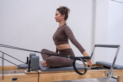 Schilderij op canvas Pilates reformer workout Woman sitting on machine performing core strengthening
