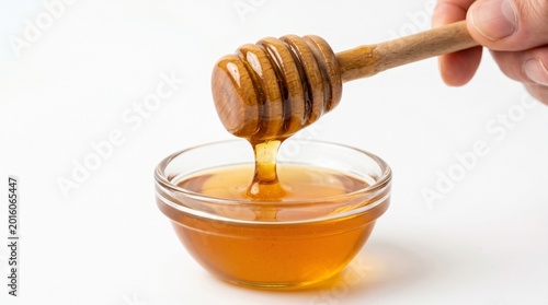 Golden Honey Dripping from Wooden Dipper into Glass Bowl