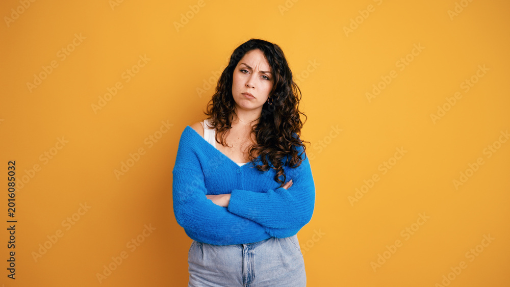 Obraz premium Woman standing with arms crossed, frowning her face, showing disappointment, annoyance, and being upset on an orange background