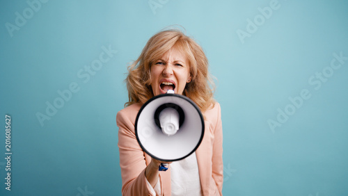 Quadro su tela Mature woman holding a megaphone, loudly making an announcement or expressing st