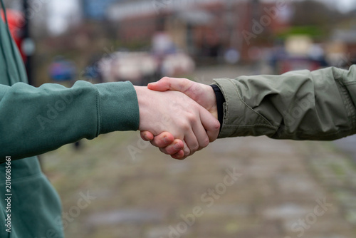 Cuadro en lienzo People shake hands in a city setting during a meeting on a cloudy day in the aft