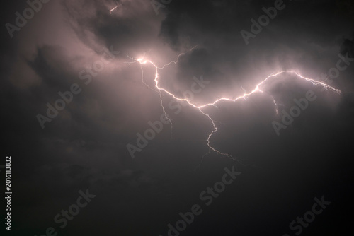 Dramatic lightning striking through dark storm clouds at night