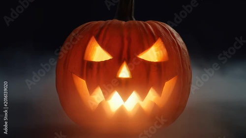 Glowing Halloween Jack O Lantern Pumpkin Carved With Scary Face In Dark Smoke.